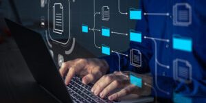 Document Management System (DMS) being setup by IT consultant working on laptop computer in office. Software for archiving, searching and managing corporate files and information. Business processes
